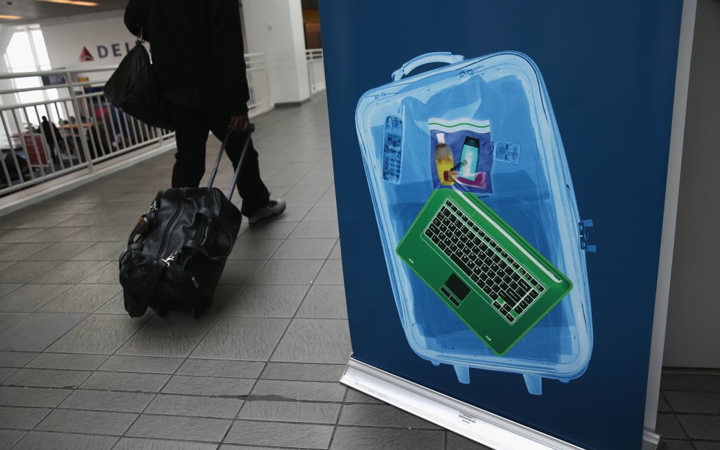 Passenger walks past sign showing x-ray screening.