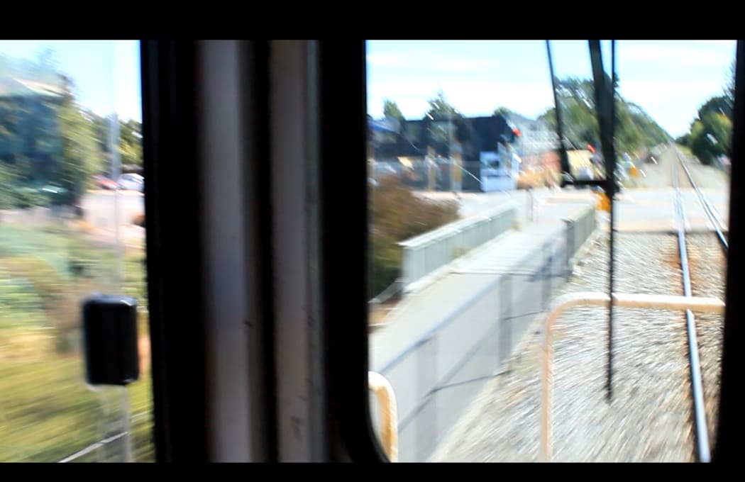 A  photo of the train approaching a level crossing at speed. Locomotive engineers are mindful that cars may challenge them at these crossings.
