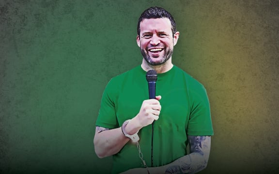 Andrew Hamilton with microphone and handcuffs