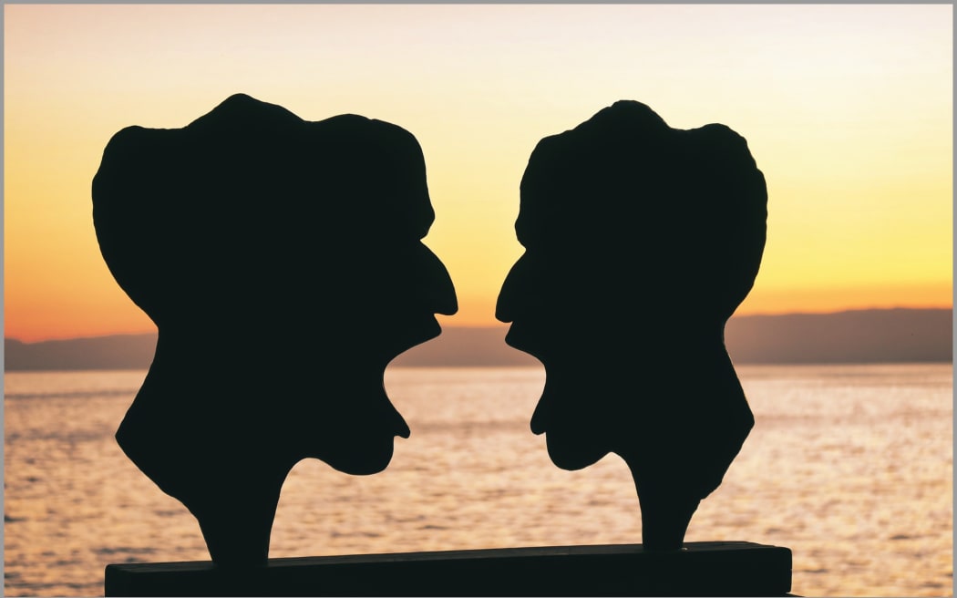 Image of two arguing statue heads.