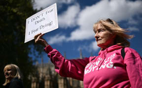 A disability campaigner from "Dignity in Dying" holds a placard as she demonstrates outside The Palace of Westminster, home to the Houses of Parliament in central London, on April 29, 2024, during a gathering in favour of the proposals to legalise assisted suicide in the UK. (Photo by Ben Stansall / AFP)