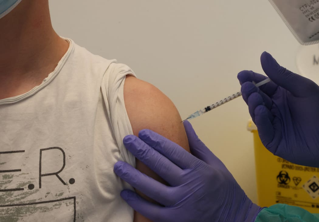 19 June 2021, Thuringia, Weimaer: 15-year-old Morris (l) receives his first vaccination against Covid 19 from Marc Gerber.