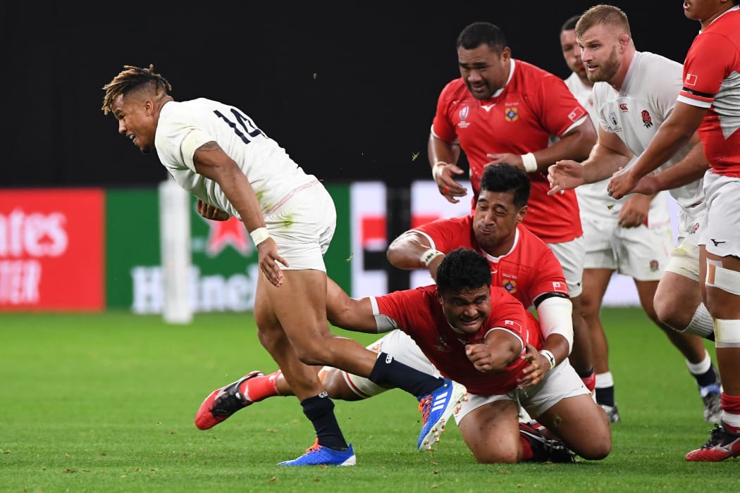 Tonga's Siua Maile grasps at England wing Anthony Watson.