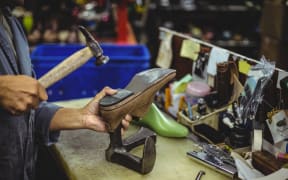 Shoemaker hammering on a shoe in workshop
