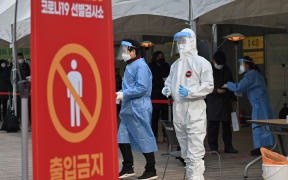 A medical staff member wearing protective gear prepares to test visitors for Covid-19 at a temporary testing station in Seoul on December 23, 2020.