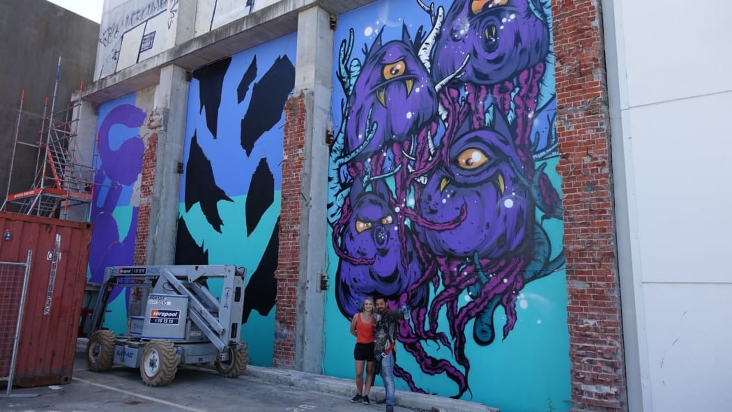 Bobby Hung (right) and assistant Danae Ripley in front of the artist's mural on Gloucester Street.