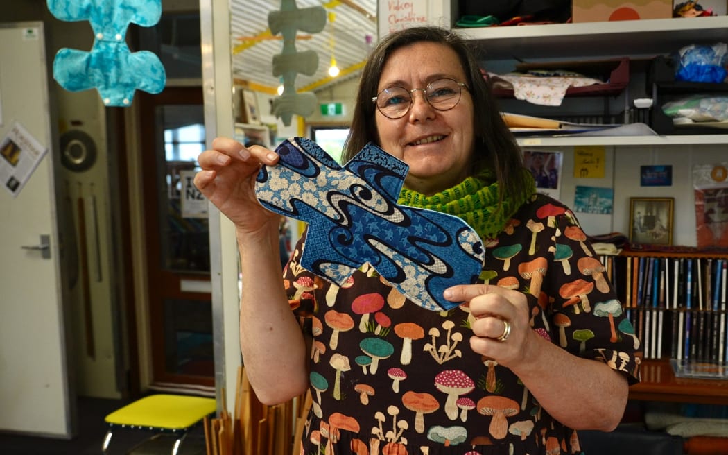 Christine Keller smiles at camera and holds a reusable period pad product.