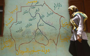 A woman walks past a map of South Sudan drawn on the wall of a polling station in April 2015.