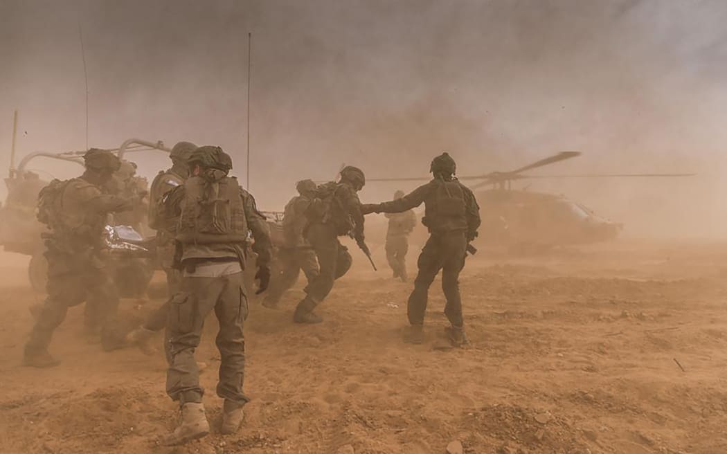 A handout picture released by the Israeli army on January 4, 2024 shows members of Unit 669 of the Israeli Air Force carrying an injured Israeli soldier to a waiting helicopter for evacuation in the Gaza Strip amid continuing battles between Israel and the Palestinian militant group Hamas.