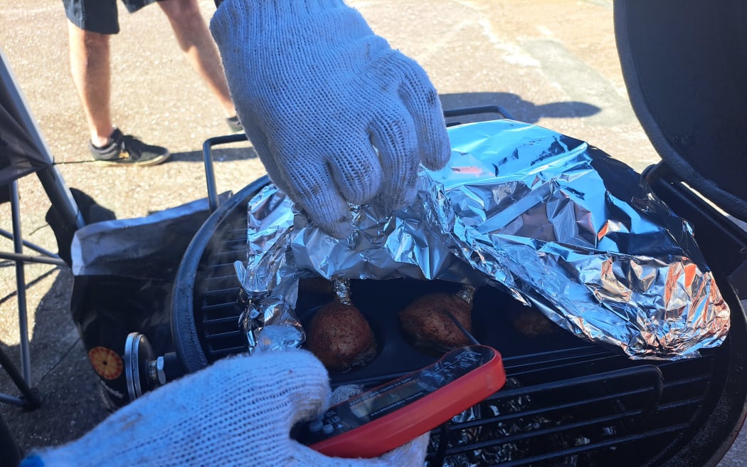 A competitive cook checks the temperature of his team's smoked chicken.