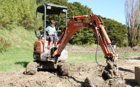 James Harold's son Axel, 7, has a go at clearing silt from their Wimbledon property.