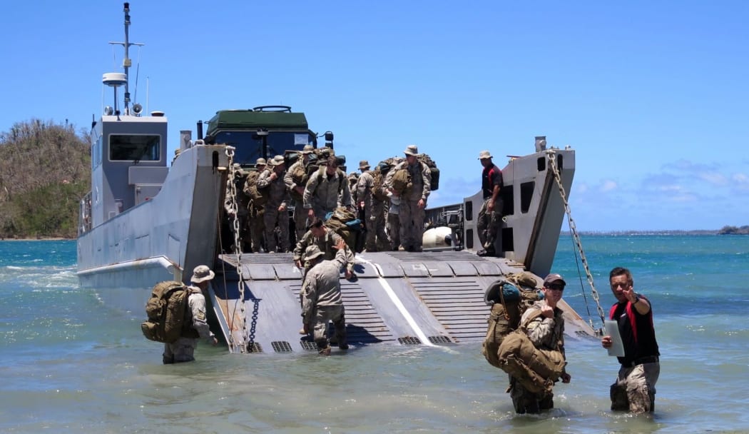 Amphibious Beach Team member Sergeant Dion Lowery guides members of the Humanitarian Assistance and Disaster Relief Light Task Force ashore.