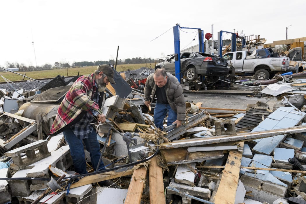 Martin Bolton (L) and shop owner Danny Wagner try to shut off a leaking gas meter after his automobile repair shop was destroyed by a tornado in Mayfield, Kentucky, on 11 December 2021.