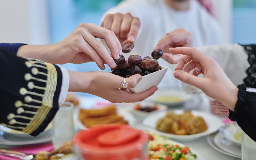Muslim family having iftar together during Ramadan. Arabian people gathering for traditional dinner during fasting month. Dates sharing to break fasting