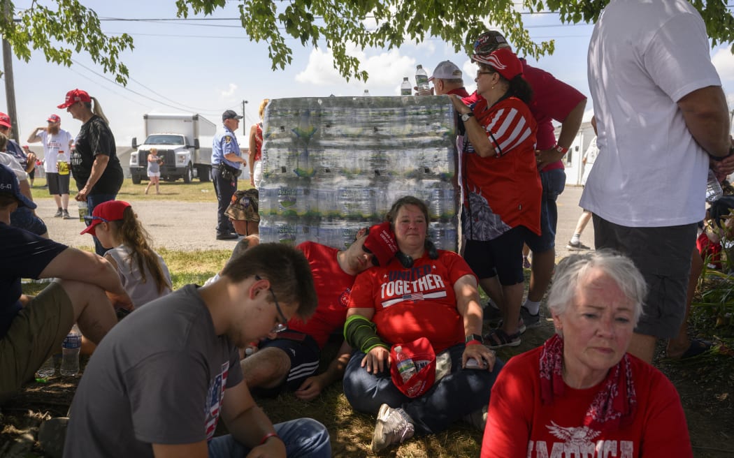 Trump supporters seek shade while waiting in 92F degree (33C) for the start of a campaign rally for former US President Donald Trump on 13 July, 2024 in Butler, Pennsylvania.