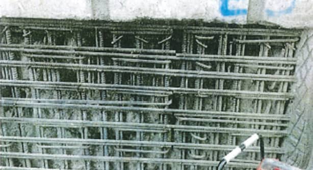 Steel reinforcing exposed by unsound concrete is prepared for repair, in the basement or near a wall.