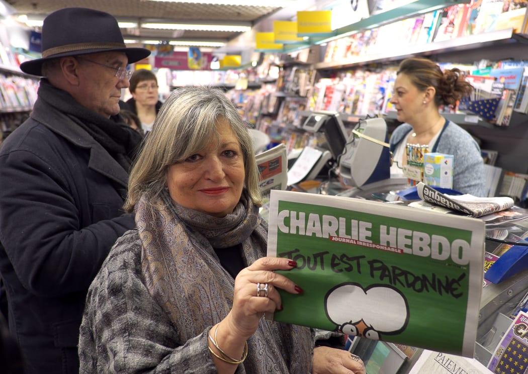 A woman displays the latest edition of French satirical magazine Charlie Hebdo shortly after it went on sale.
