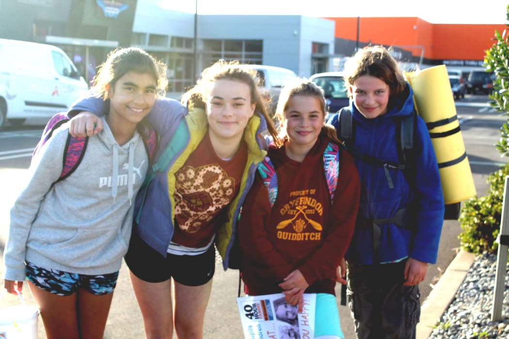 A photo of four pupils from Sumner School in Ferrymead, laden with backpacks and  preparing for the walk to Sumner