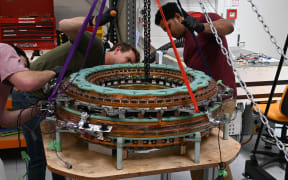 Two people crouch around a piece of nuclear technology.