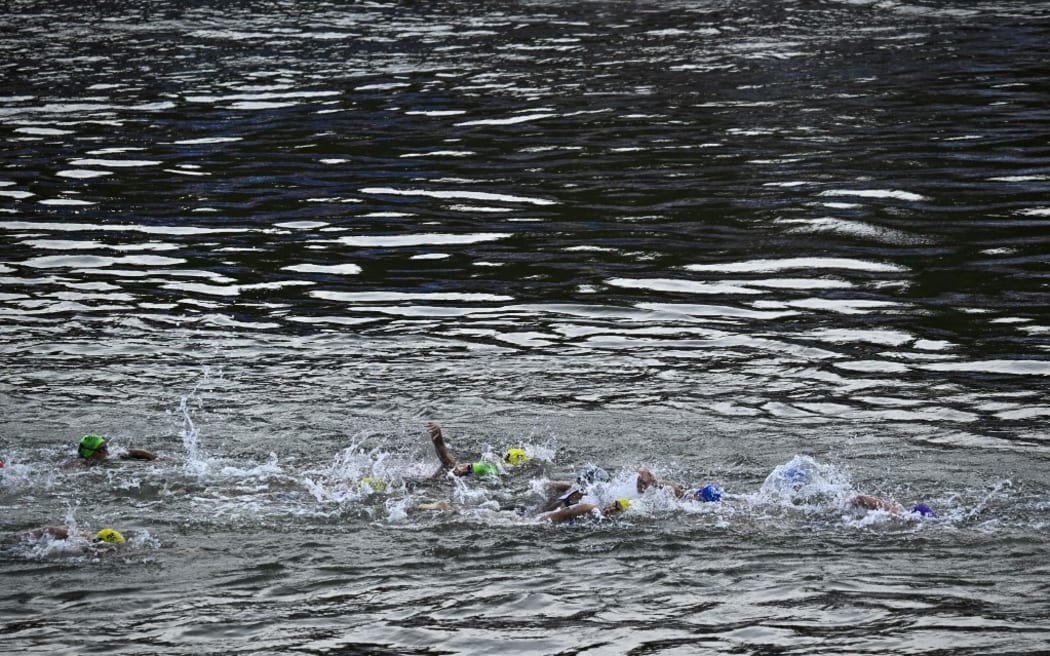 Athletes compete in the swimming race in the Seine during the women's individual triathlon at the Paris 2024 Olympic Games in central Paris on July 31, 2024. (Photo by JULIEN DE ROSA / AFP)