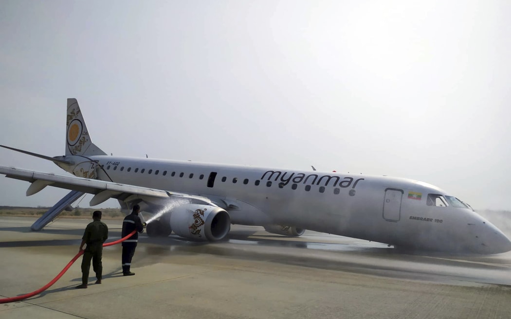 Firefighters at Mandalay aiport work on a plane that pilots landed safely after the front wheels failed to deploy.