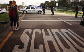 Two women hug near at the police checkpoint at the Marjory Stoneman Douglas High School, where 17 people were killed by a gunman.