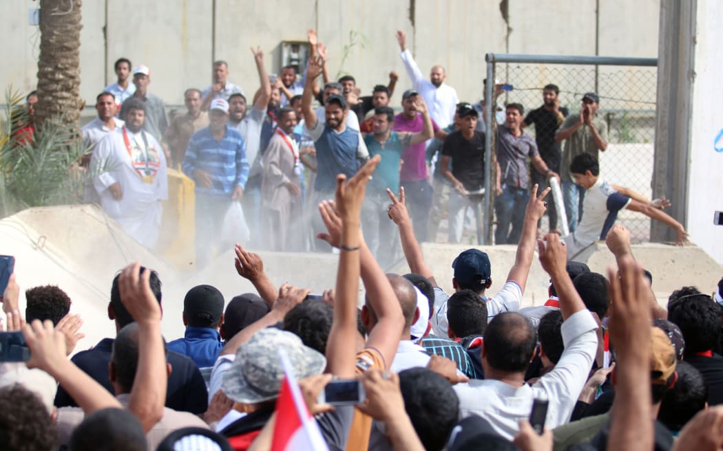 Iraqi protesters celebrate as they open a breach in a concrete wall surrounding the parliament after breaking into Baghdad's heavily fortified "Green Zone" on April 30, 2016.