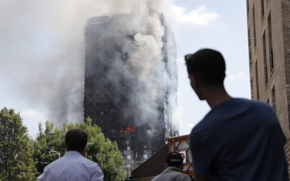 People look up towards Grenfell Tower as daylight revealed the 24-storey block still burning.