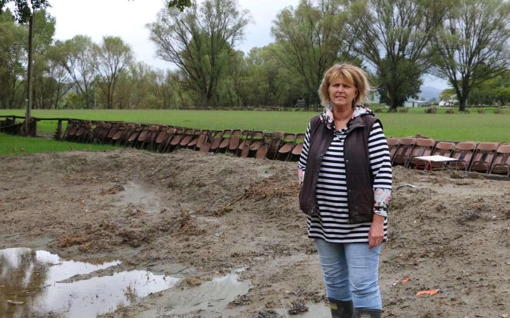 A woman stands in a muddy field.