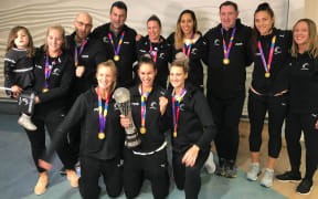 Silver Ferns Sharon Saunders, Ameliaranne Ekenasio and Jane Watson (front, L-R), Phoenix Karaka (rear, fourth from right), Karin Burger (rear, second from right) and team staff show off the Netball World Cup after landing at Auckland Airport.