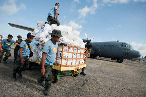 Philippine police help load an RNZAF C-130 Hercules with food for typhoon survivors.