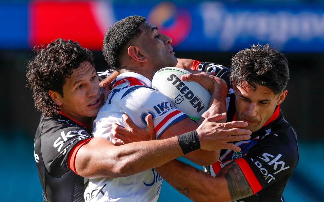 Dallin Watene-Zelezniak and Jesse Arthars tackle Daniel Tupou during the Sydney Roosters match against the Vodafone Warriors in Sydney.