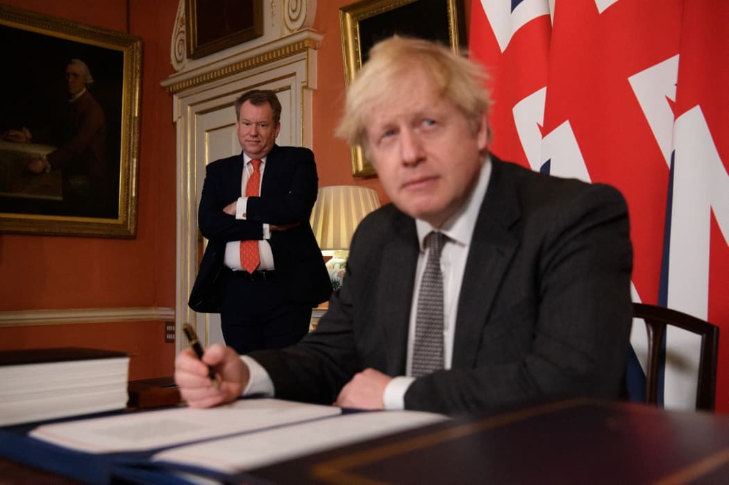 UK chief trade negotiator, David Frost (L) looks on as Britain's Prime Minister Boris Johnson (R) signs the Trade and Cooperation Agreement between the UK and the EU, the Brexit trade deal, at 10 Downing Street in central London on December 30, 2020.