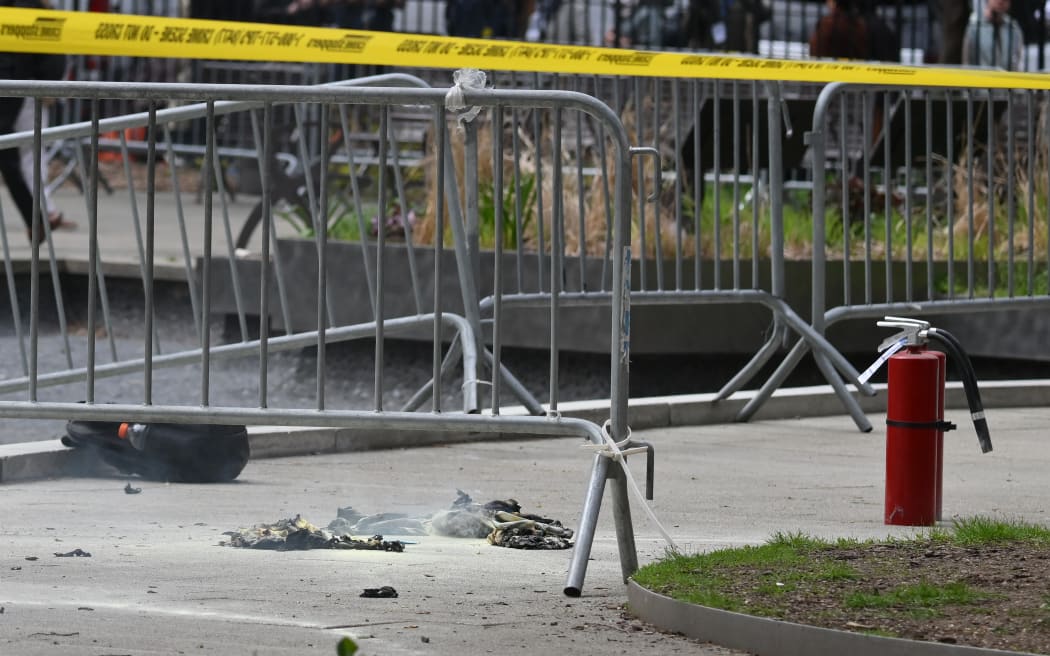 Fire extinguishers (R) and a backpack (L) are left at the park across from Manhattan Criminal Court in New York City after a man reportedly set himself on fire during the trial of US President Donald Trump, in New York City on April 19, 2024. A man set himself on fire Friday outside the court, New York police said, with officers rushing to extinguish the flames. TV reporters described the scene that unfolded moments after the full panel of 12 jurors and six alternates was selected for the trial of the former president in a hush money cover-up case. (Photo by ANGELA WEISS / AFP)