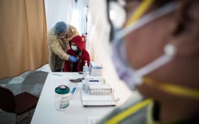 A doctor examines a patient for a COVID-19 test inside a testing tent in New York.