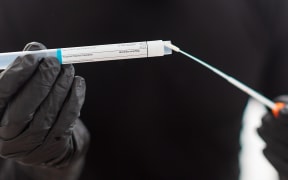 Covid-19 respiratory sputum specimen swab test tube with gloves.