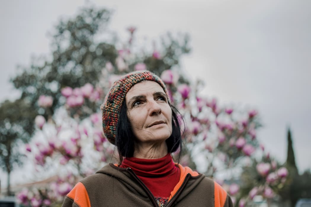Nadmea Carvalho stands in front of some flowers outside her home in Tāmaki