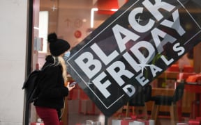 A pedestrian wearing a mask because of the novel coronavirus pandemic walks past a shop advertising Black Friday sales on Oxford Street in London on November 26, 2020.