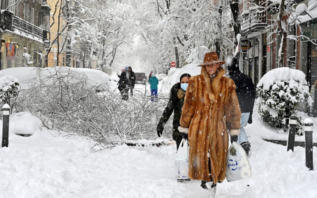 A woman wearing a fur coat walks amid a heavy snowfall in Madrid on January 9, 2021.