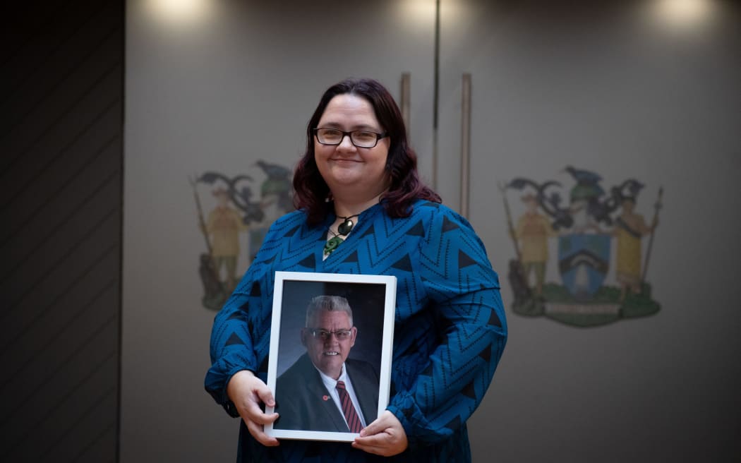Elizabeth Sturt stands in front of Rotorua Lakes Council chambers with a picture of her late father and former councillor, Charles Sturt.