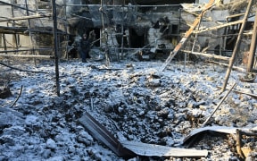 A Ukrainian rescuer works at the site of an airstrike in Kharkiv on January 1, 2026, amid the Russian invasion of Ukraine. (Photo by SERGEY BOBOK / AFP)