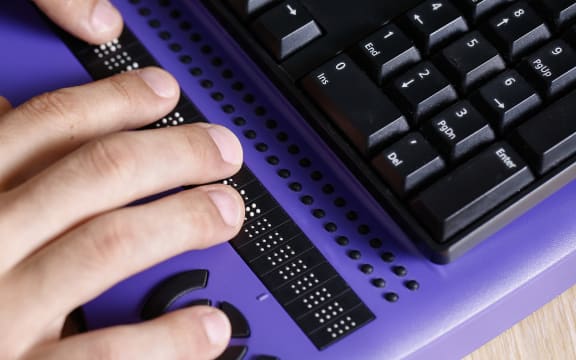 Blind person using computer with braille keyboard. Visual impairment, independent life concept.