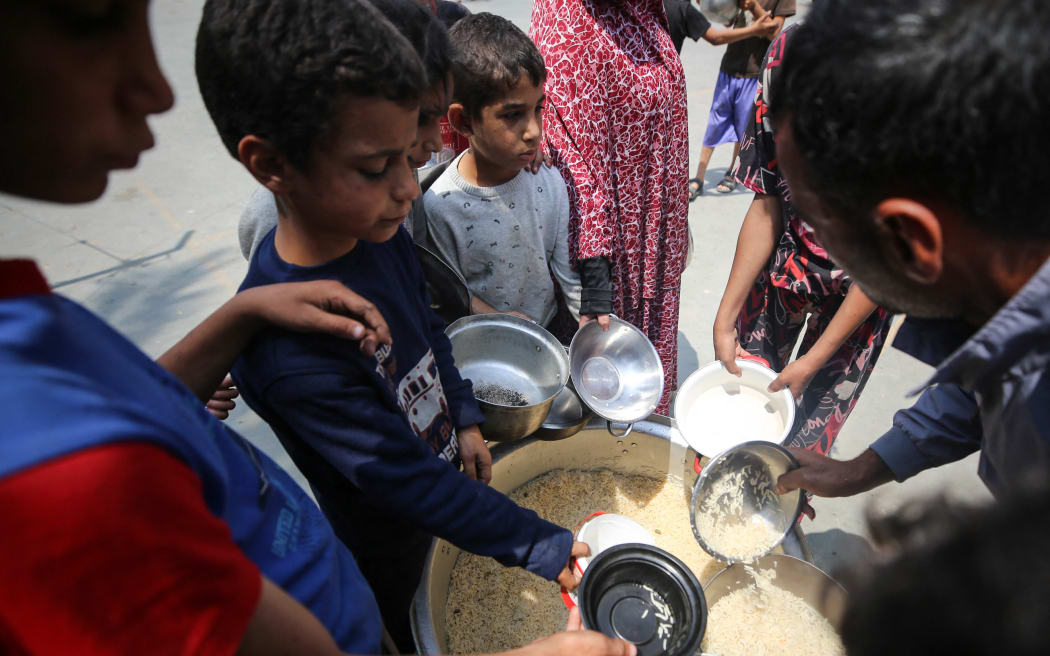 Palestinians are gathering to receive food meals cooked by World Central Kitchen (WCK) after the charity resumed operations at a school sheltering displaced people, amid the ongoing conflict between Israel and Hamas, in Deir Al-Balah in the central Gaza Strip, on May 1, 2024.