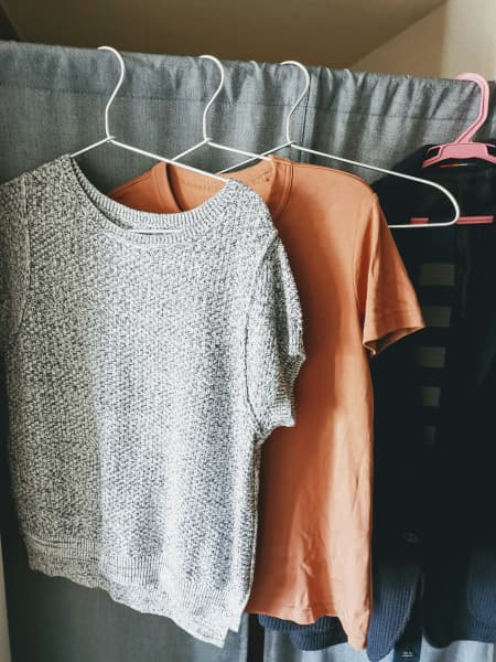 Clothes on hangers on a curtain frame.