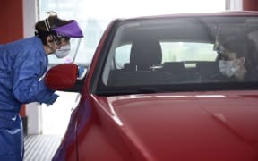 A health worker dressed in protective gear takes samples from a driver at a drive-through testing centre for the Covid-19 disease at Donostia Hospital in San Sebastian on 25 March .