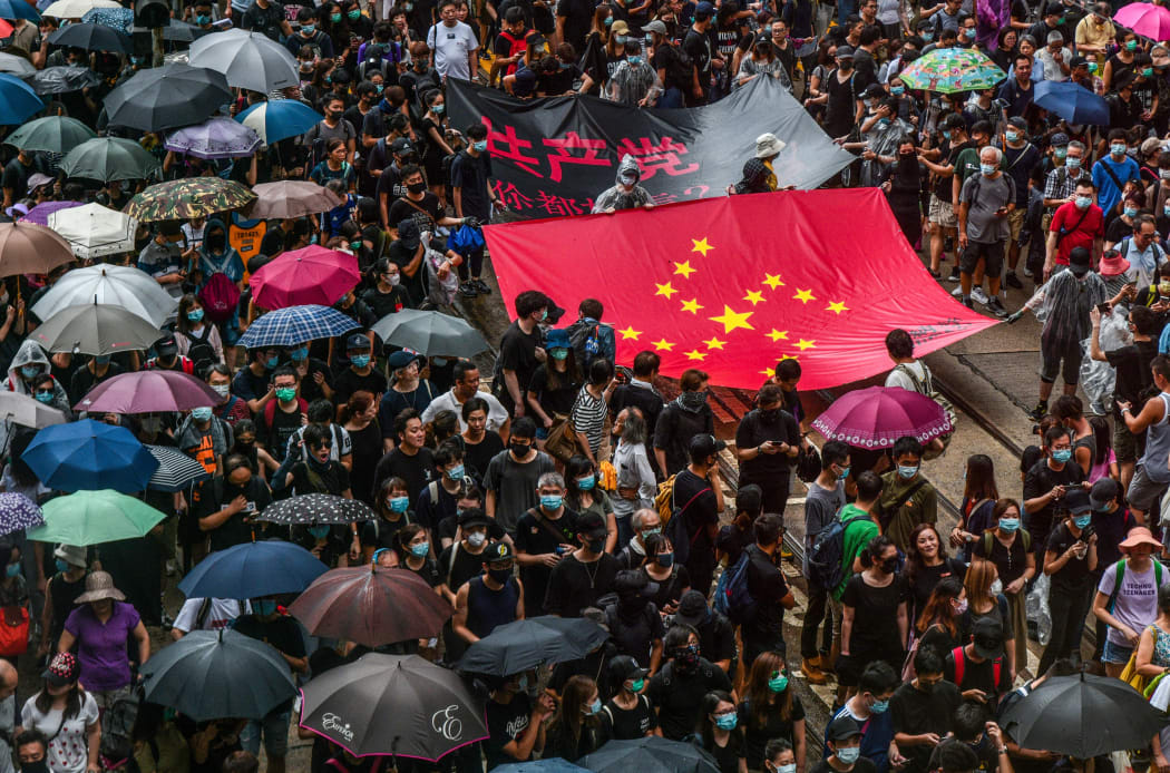 Protesters march with a banner that uses the stars of the Chinese national flag to depict a Nazi Swastika symbol in the Central district of Hong Kong on August 31, 2019.