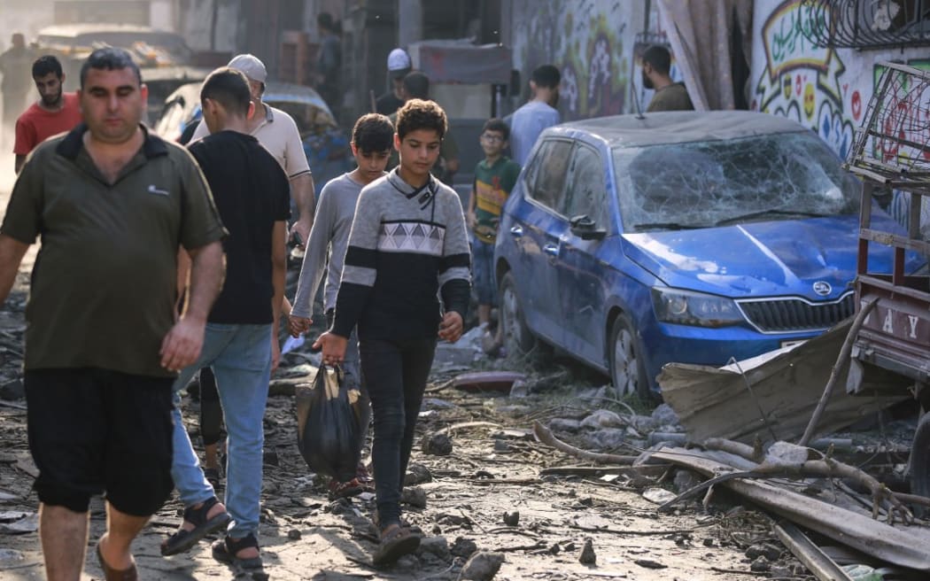 Palestinians walk past debris a day after an Israeli strike in the Jabalia camp for Palestinian refugees in the Gaza Strip, on November 1, 2023.