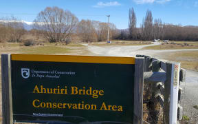Blues skies, snow clad mountains in the background and a DOC sign