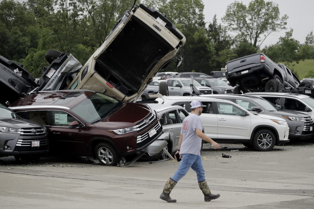 A worker walks past tornado-damaged cars at a dealership in Jefferson City, Missouri.