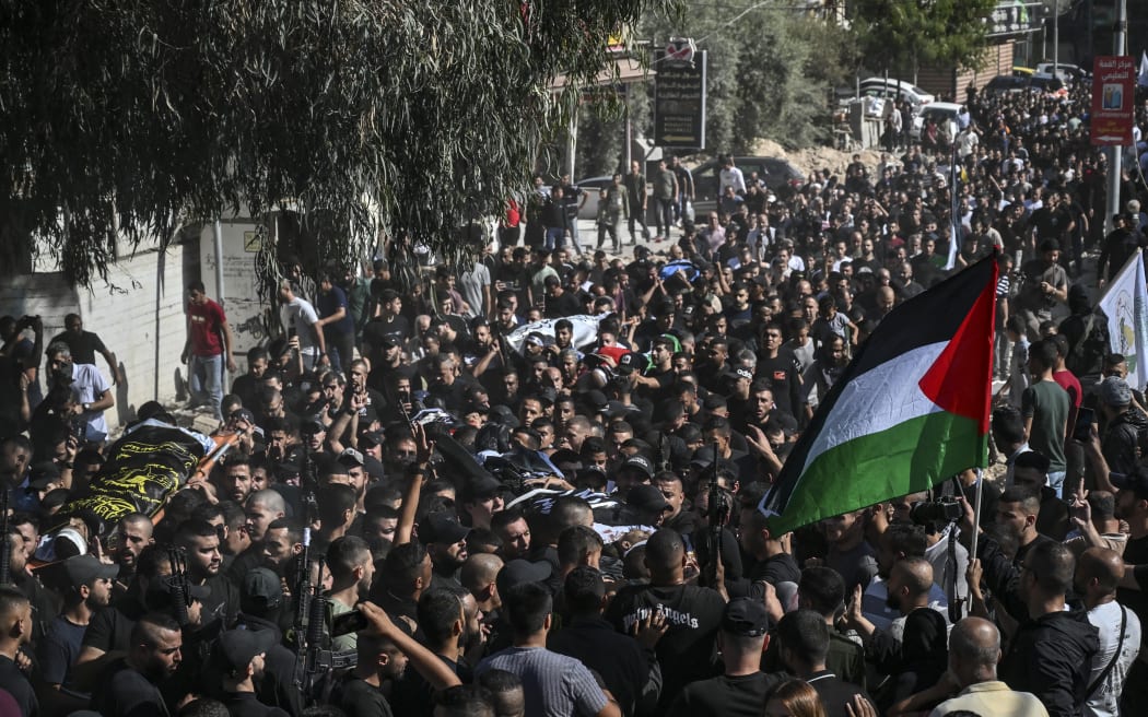 People carry the flag-draped bodies of men killed during an Israeli raid followed by clashes with Palestinians, in the occupied West Bank Jenin refugee camp, during their funeral on November 10, 2023.